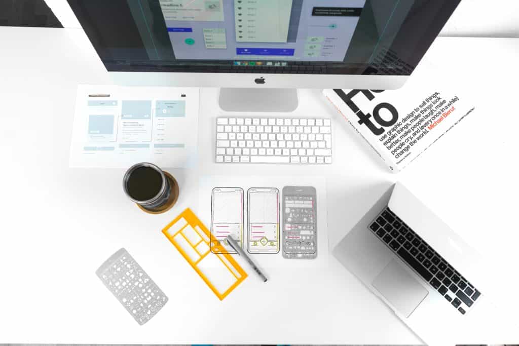 Desktop and laptop computers on a desk with sketches of responsive web design